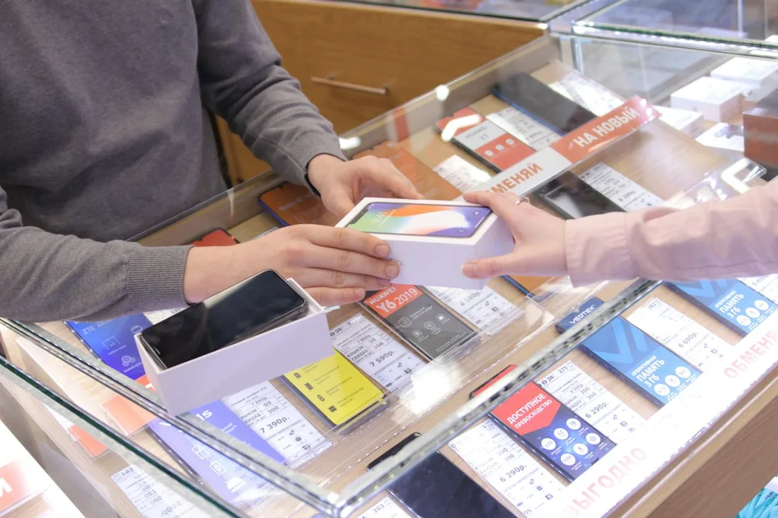 Customer and shop assistant at a counter with a mobile phone